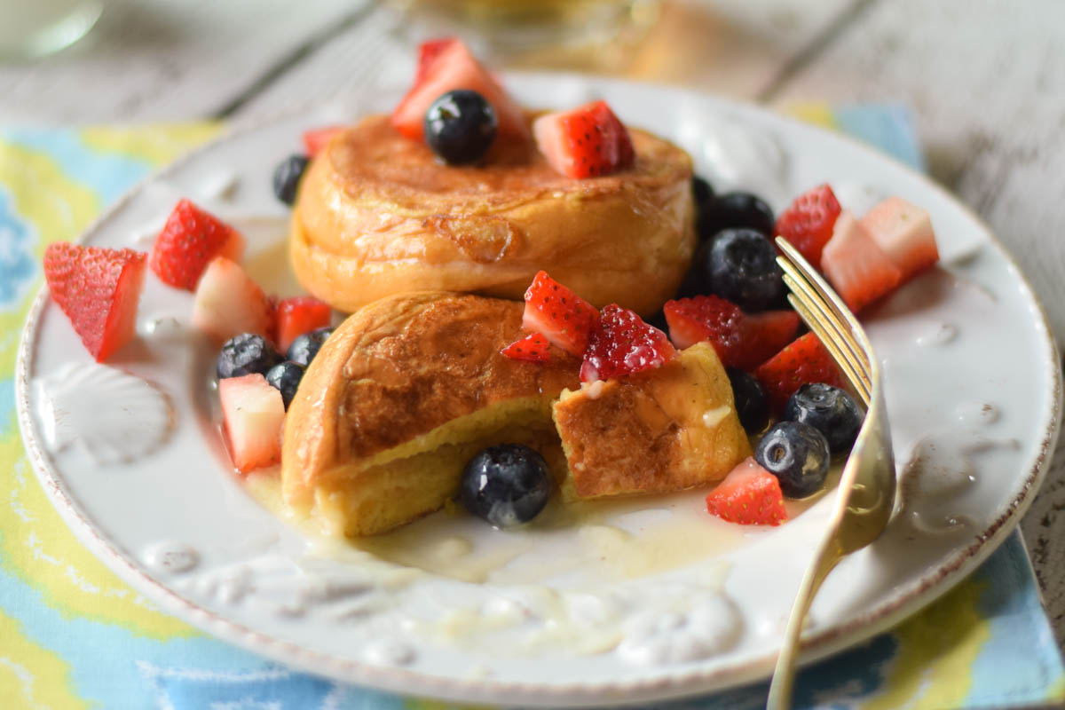 A plate of french toast with fruit and syrup topping.