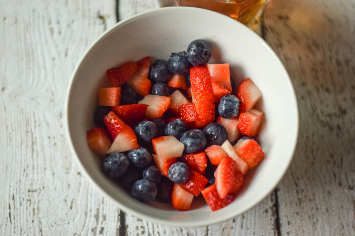 A white bowl filled with diced strawberries and blueberries.