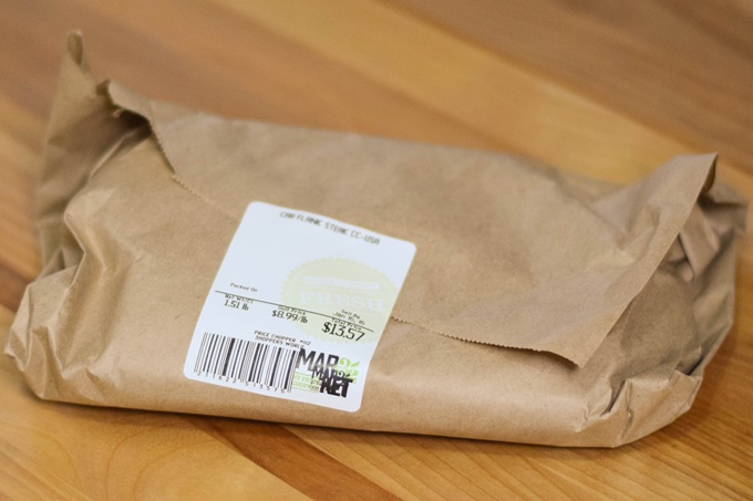Brown packaging wrapping a raw steak.