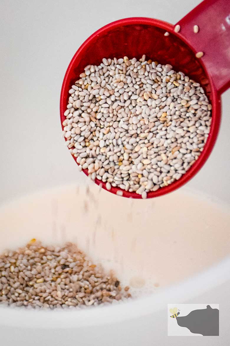 Chia seed in tablespoon being poured into liquid.