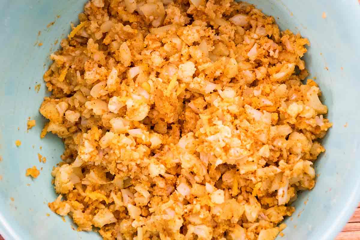 Cauliflower rice mixed with taco seasoning in a large mixing bowl.