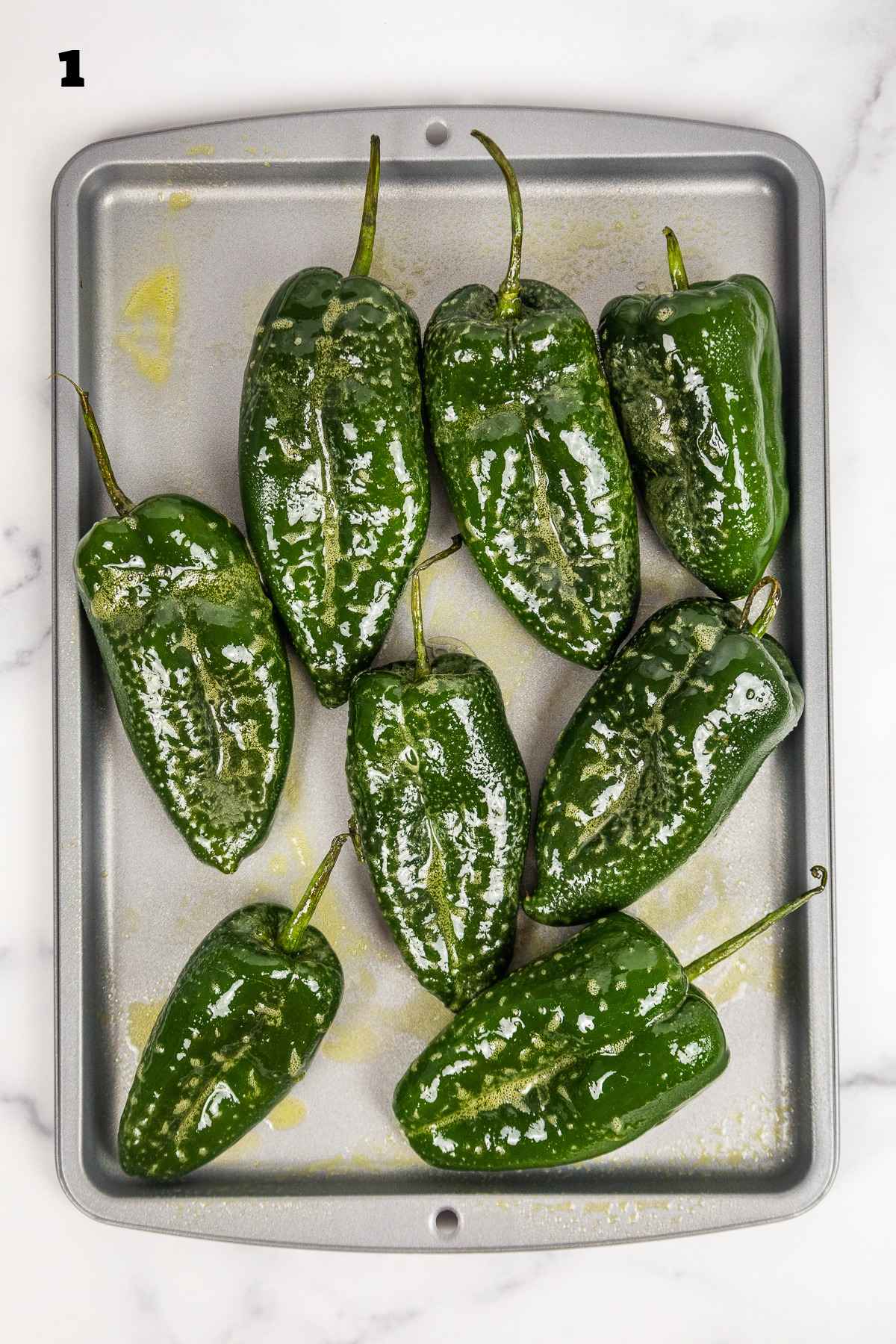 Raw peppers sprayed with cooking spray and on a baking sheet.