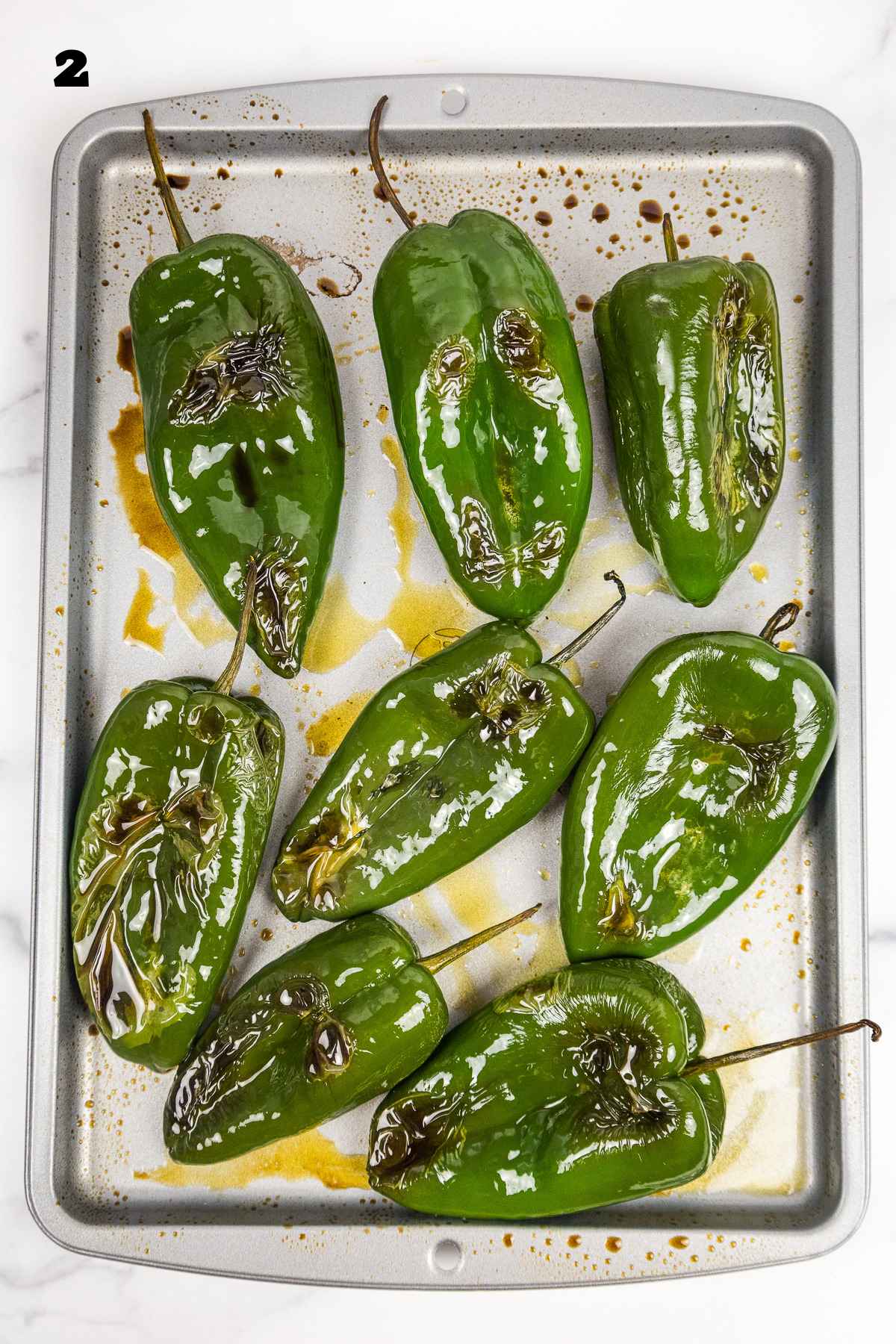 Charred pasilla peppers on a baking sheet.