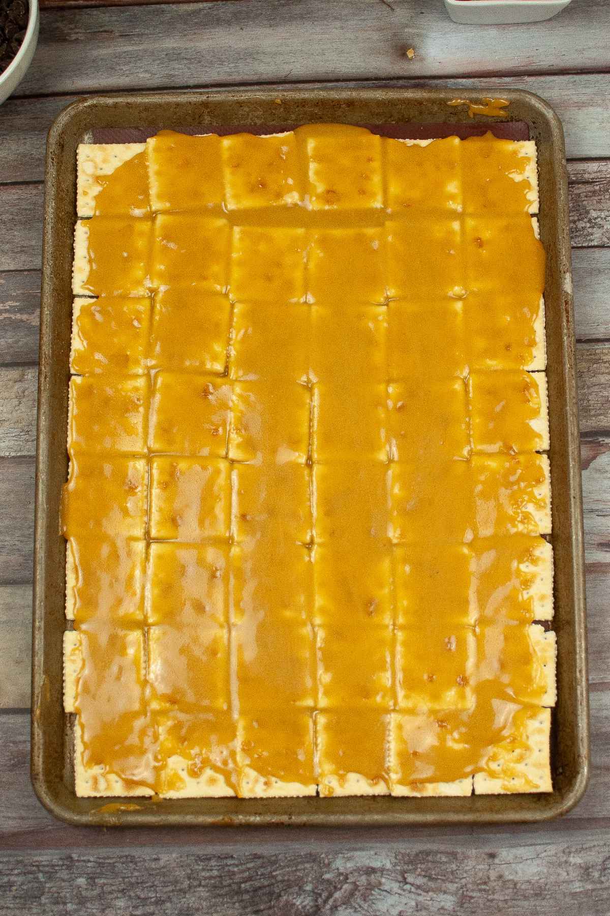 Toffee poured over saltine crackers on a jelly roll pan.