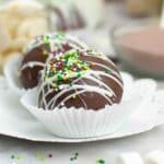 Upclose image of Christmas Hot Cocoa Bomb in a white cupcake liner on a white plate.