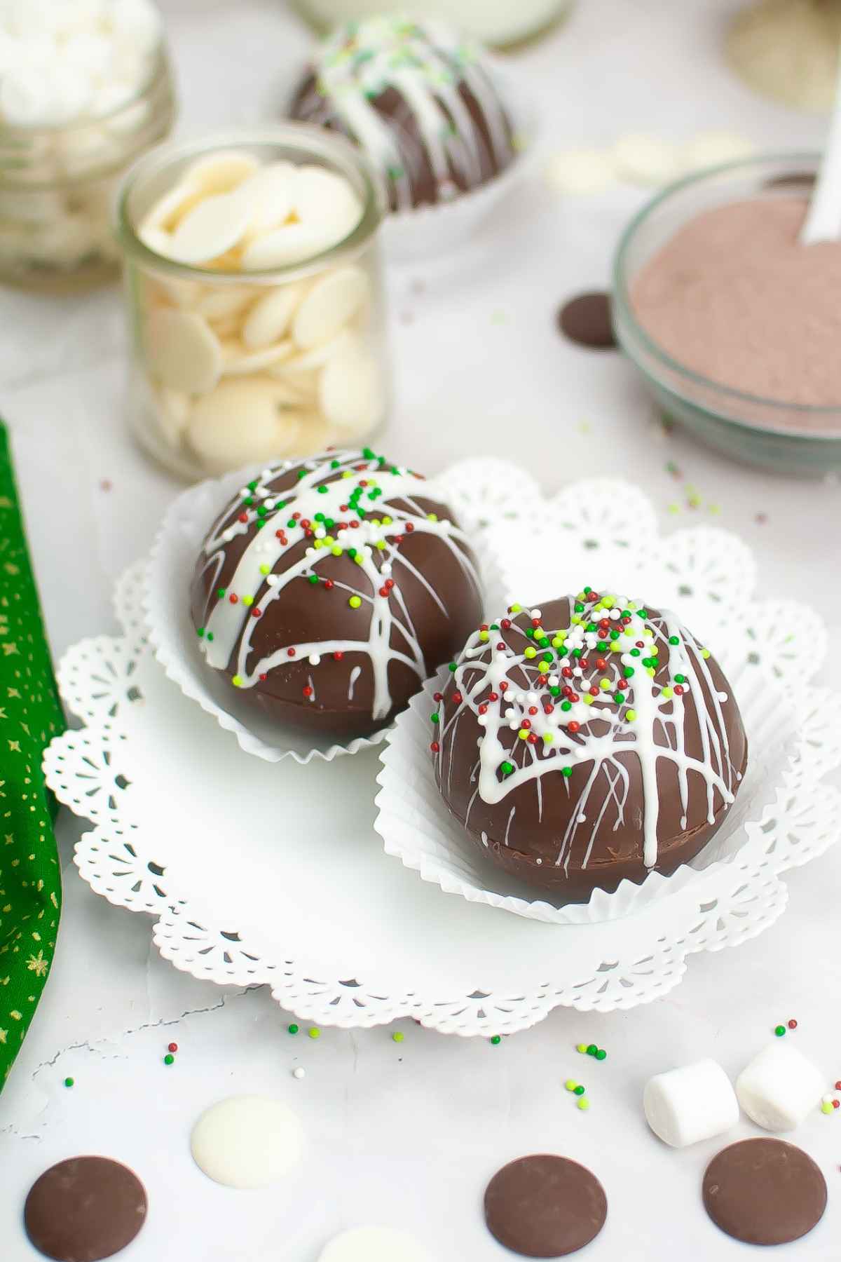 Two Christmas Hot Cocoa Bombs on a white plate in a white cupcake liner.