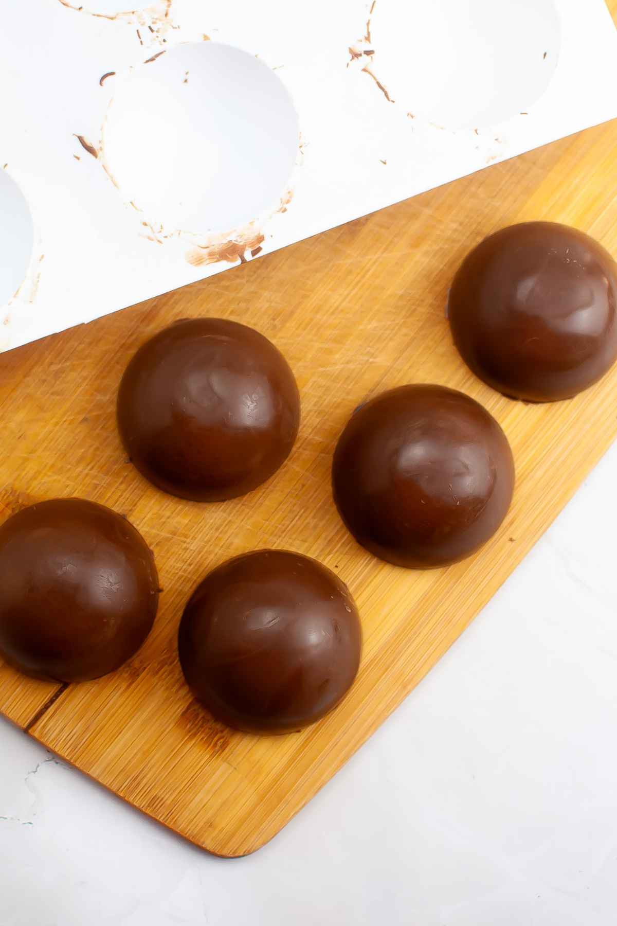 Half chocolate spheres on a wooden board.