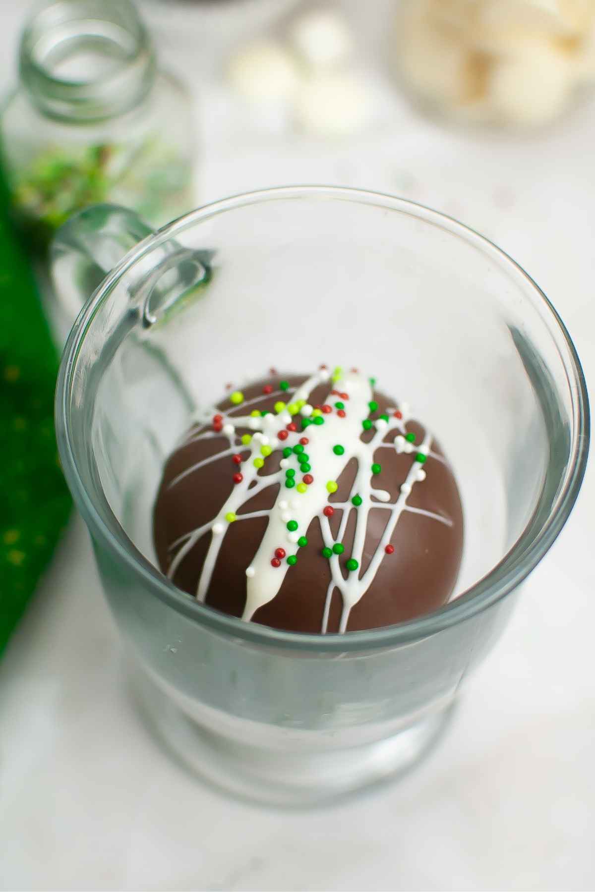 Hot cocoa bomb in a clear glass mug.