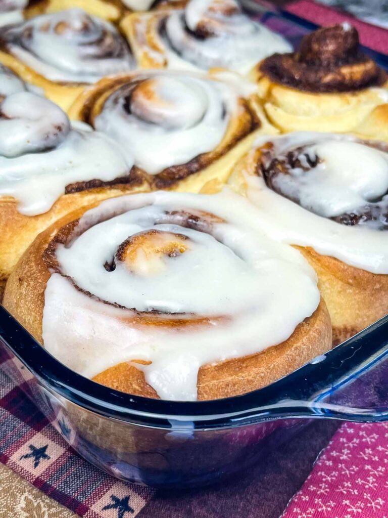 Baked clone of a cinnabon recipe with icing in the baking dish.