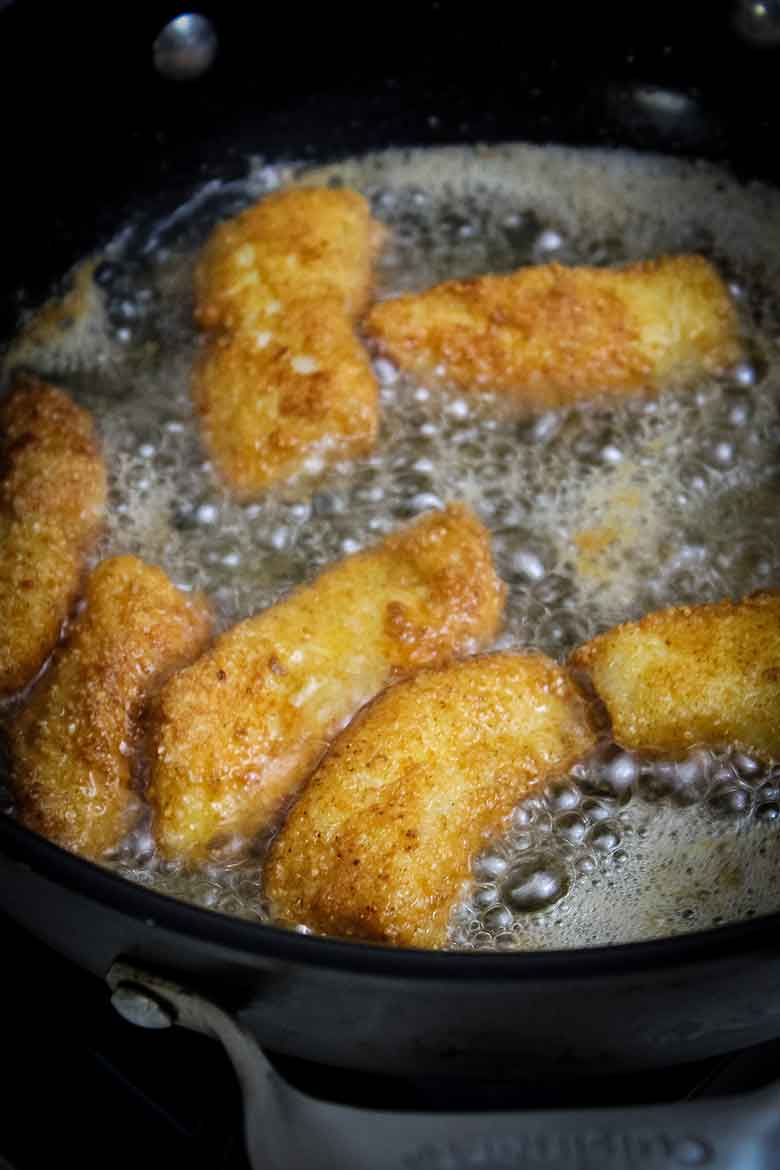 Frying cod fish in a cast iron skillet in hot oil