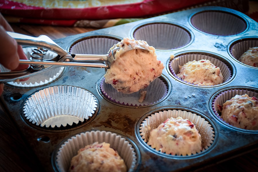 Scooping muffin batter in a tin.