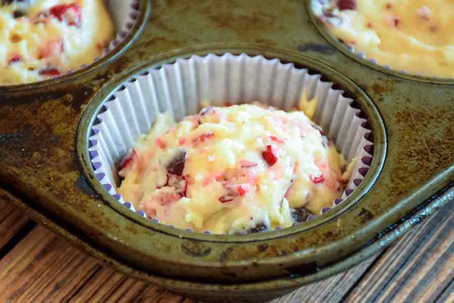 Muffin batter in scooped into non-stick paper liner liner in a muffin pan.