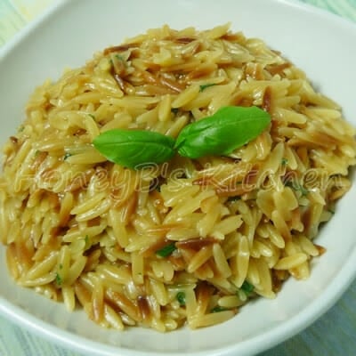 A bowl of cooked rice shaped pasta with basil garnish.