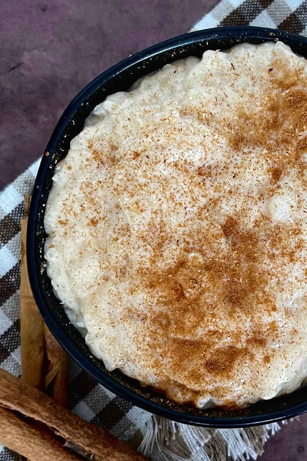 Up close image of creamy rice pudding made with sweetened condensed milk in a dark brown bowl.