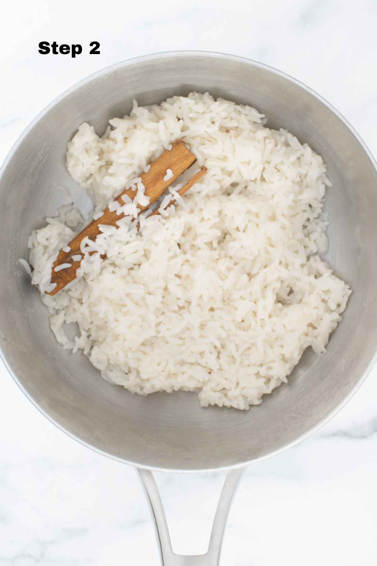 Cooked rice with cinnamon stick in cooking pot.