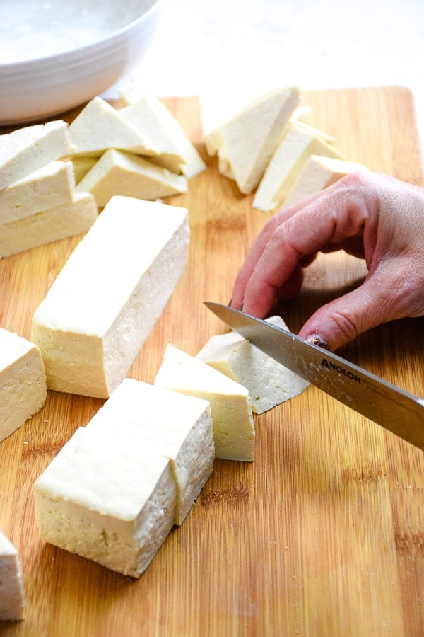 Cutting firm tofu into triangular shape.