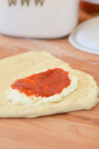 Pizza dough with ricotta cheese and sauce layer.