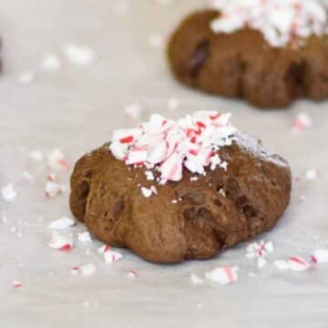Double Chocolate Peppermint Cookies topped with crushed peppermint on white parchment paper.