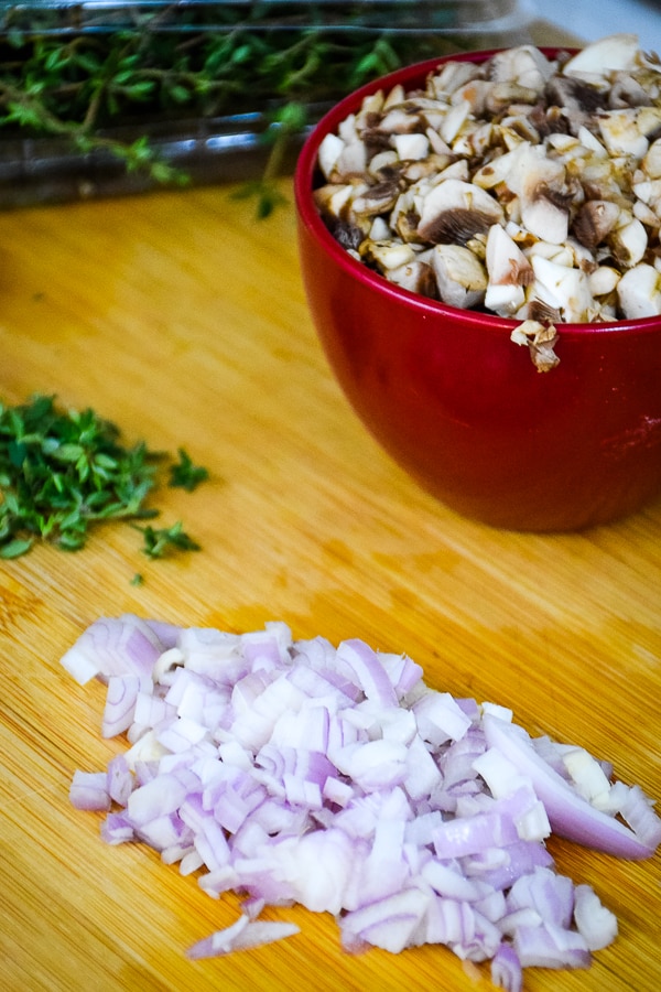 Shallots, mushrooms and thyme on cutting board.