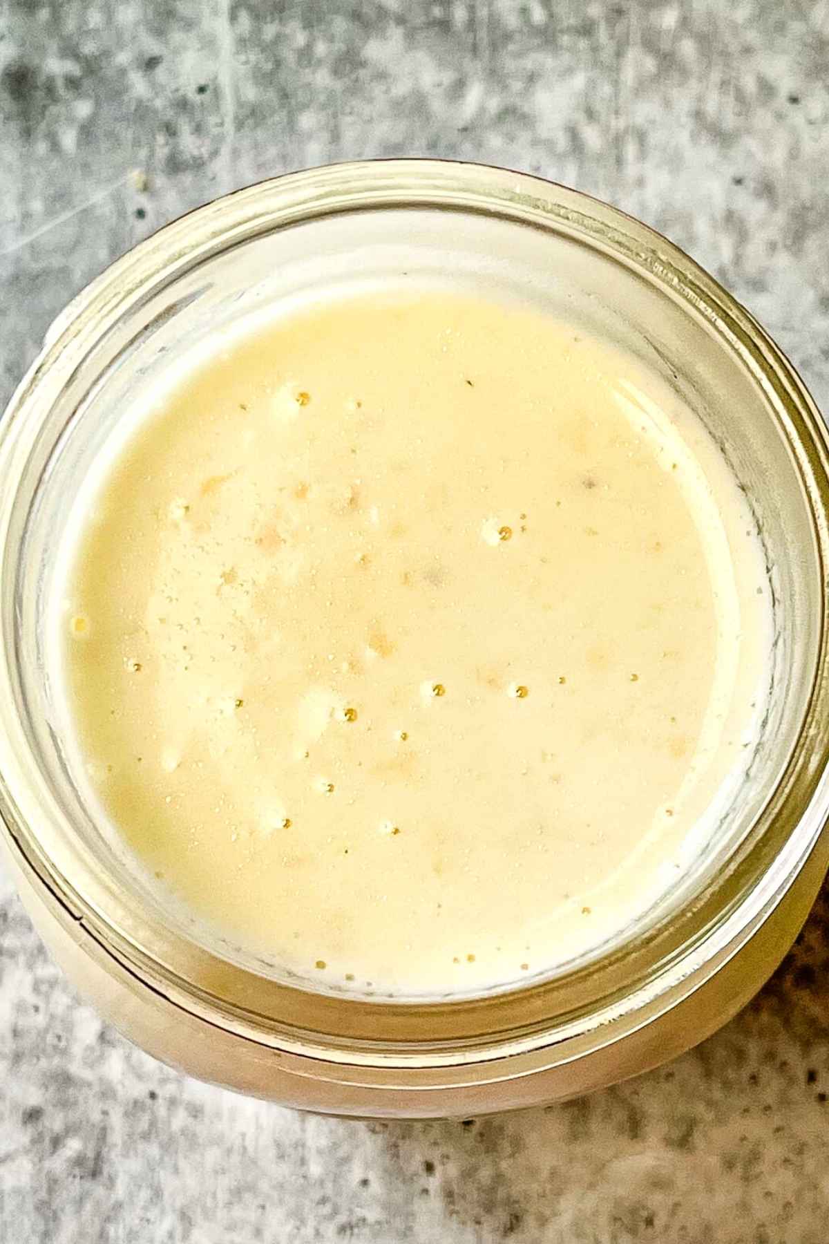 Looking inside the jar of creamy homemade alfredo sauce.