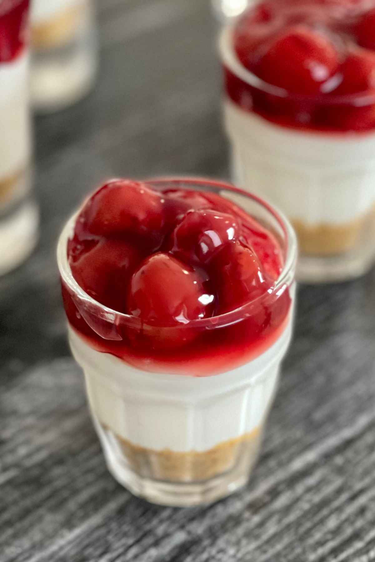 Fireball Cheesecake shots made with graham cracker crust, no bake cheesecake, fireball whisky and cherry topping.