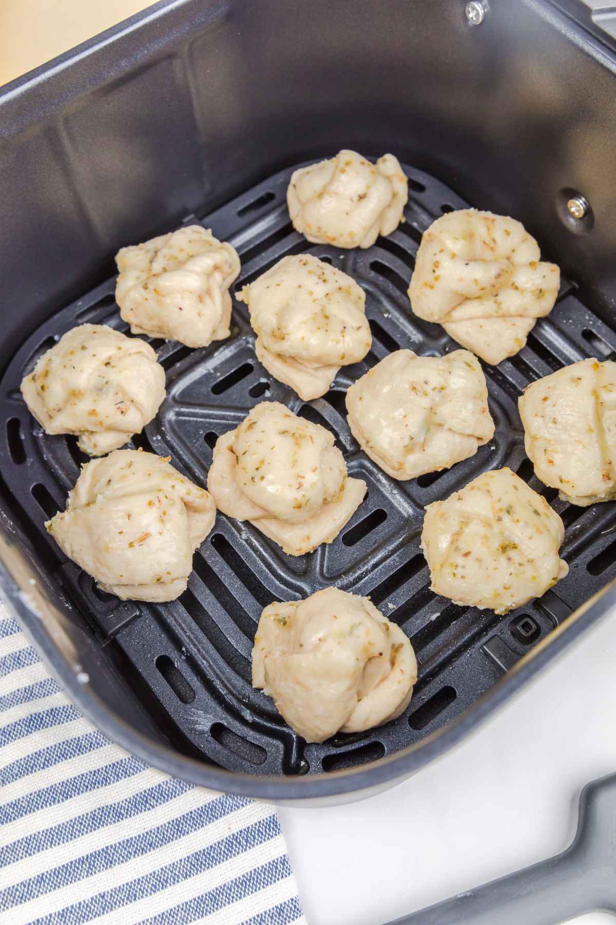Seasoned dough knots in an air fryer basket.