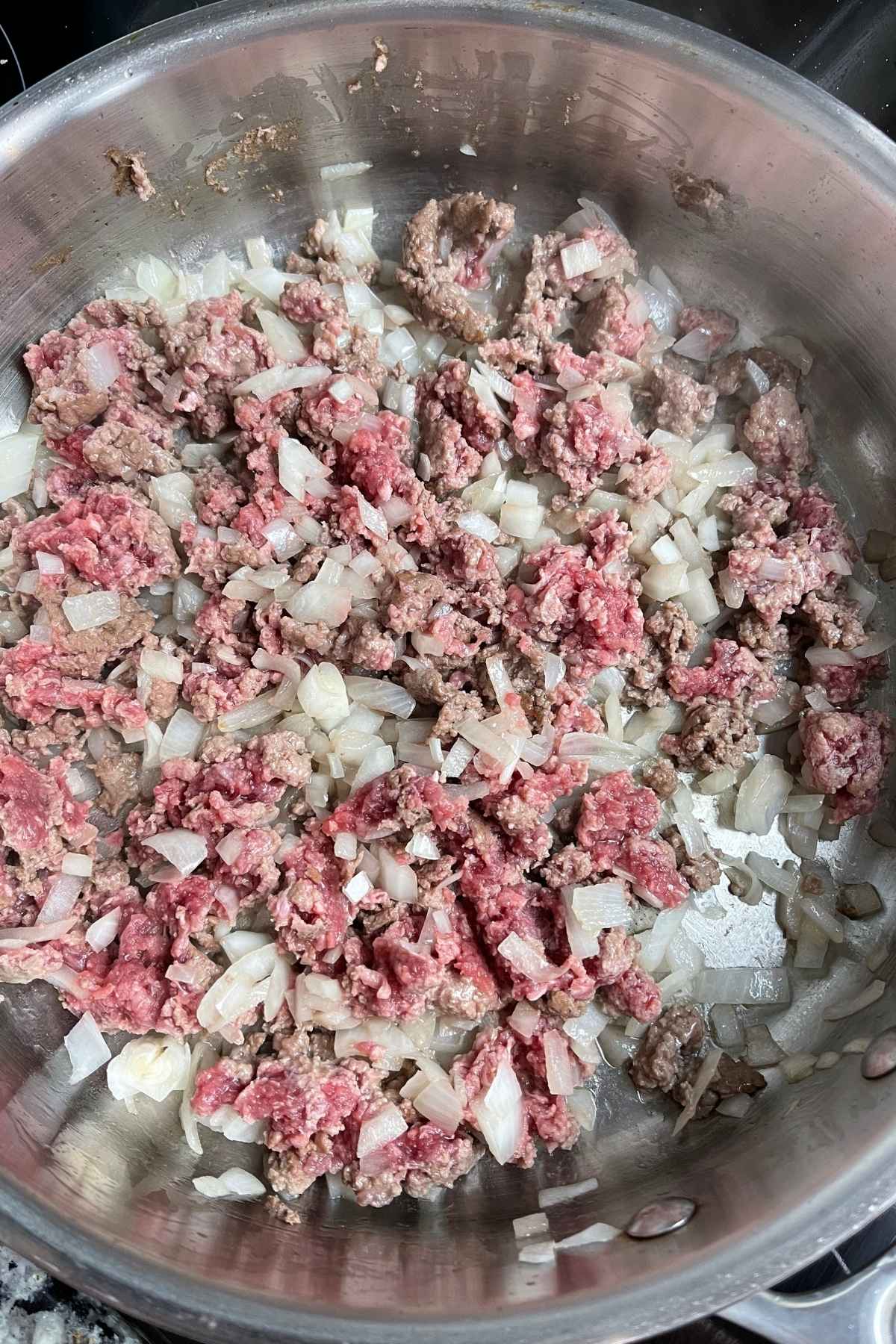 Ground beef and onions cooking in a skillet.