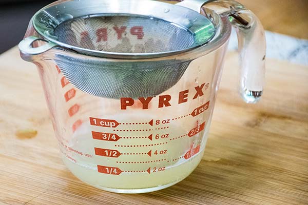 Glass measuring cup with a strainer and lime juice.