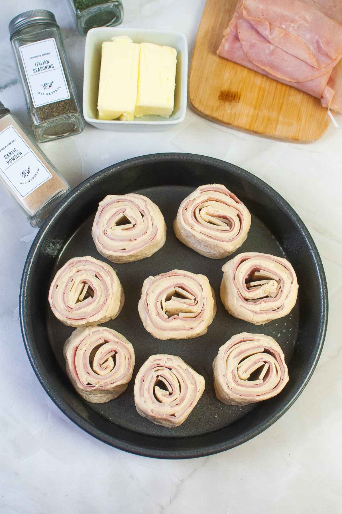 Raw roll ups with ham and cheese in a baking dish for the air fryer.