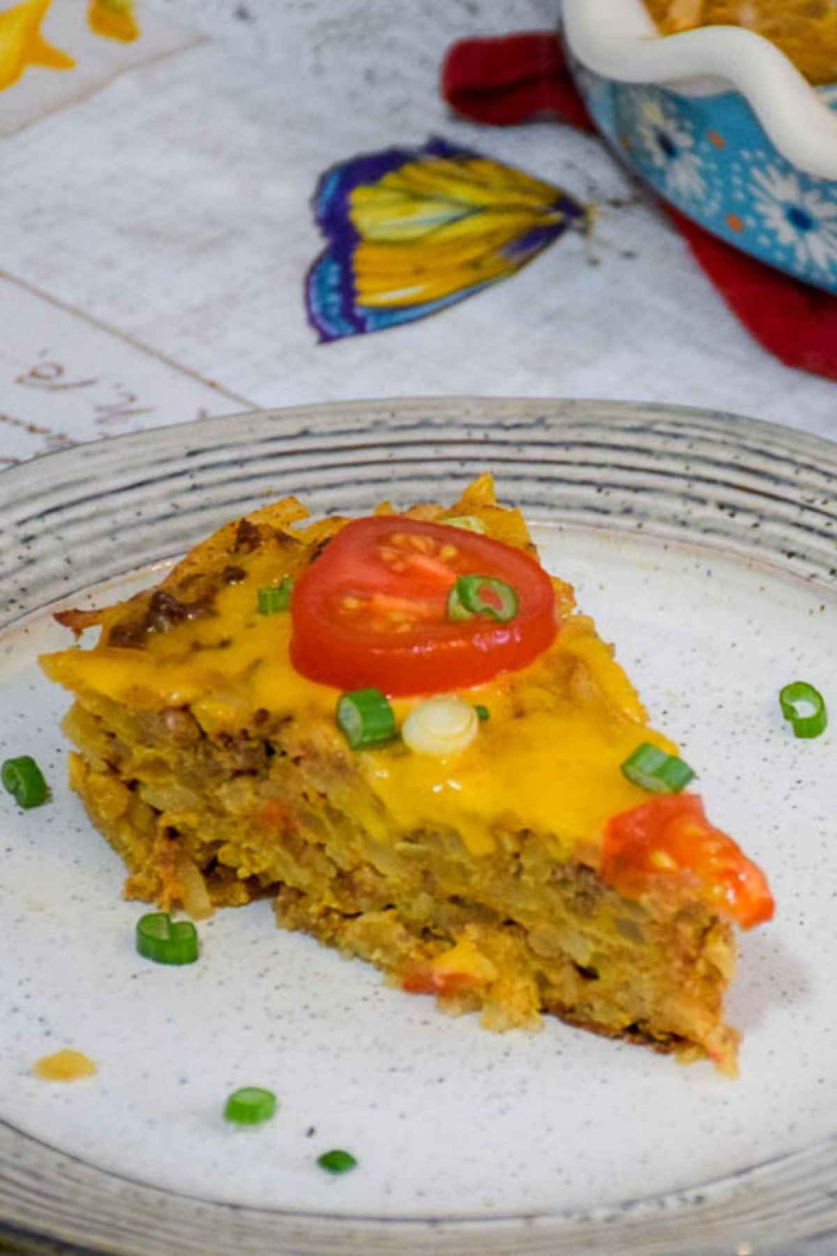 A piece of taco pie on a plate garnished with green onion tops.