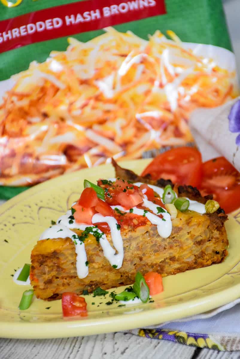 A serving of hash brown taco casserole on a yellow plate with toppings.