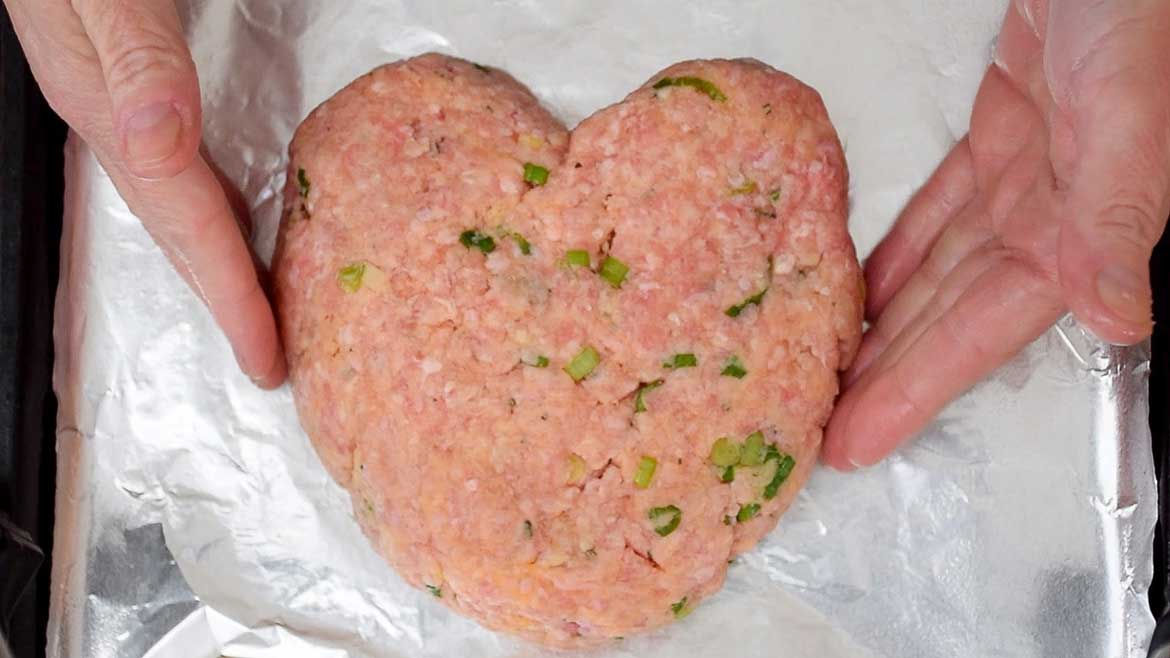 Unbaked Heart Shaped Meatloaf on a foil lined baking sheet.