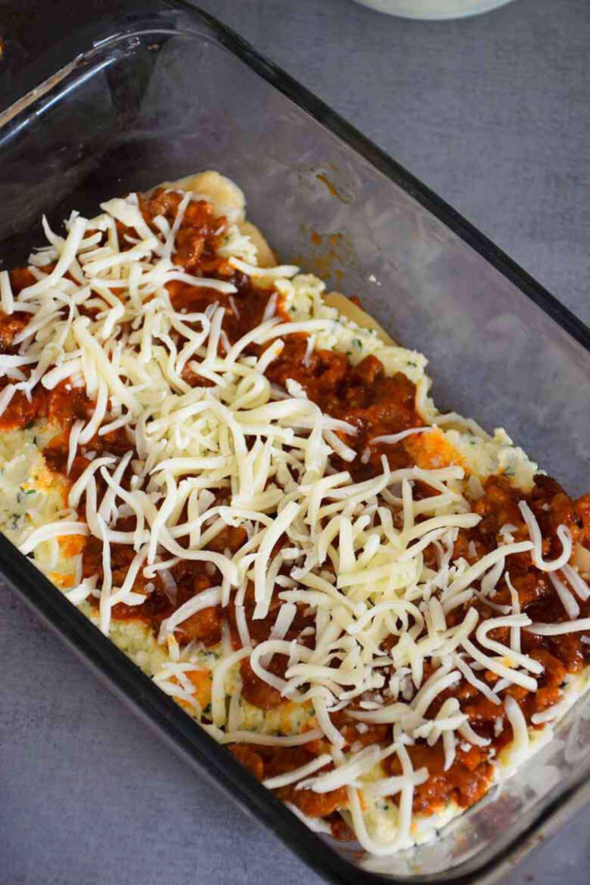 Loaf pan showing layers of palmini sheets, ricotta cheese mixture, meat sauce and mozzarella.