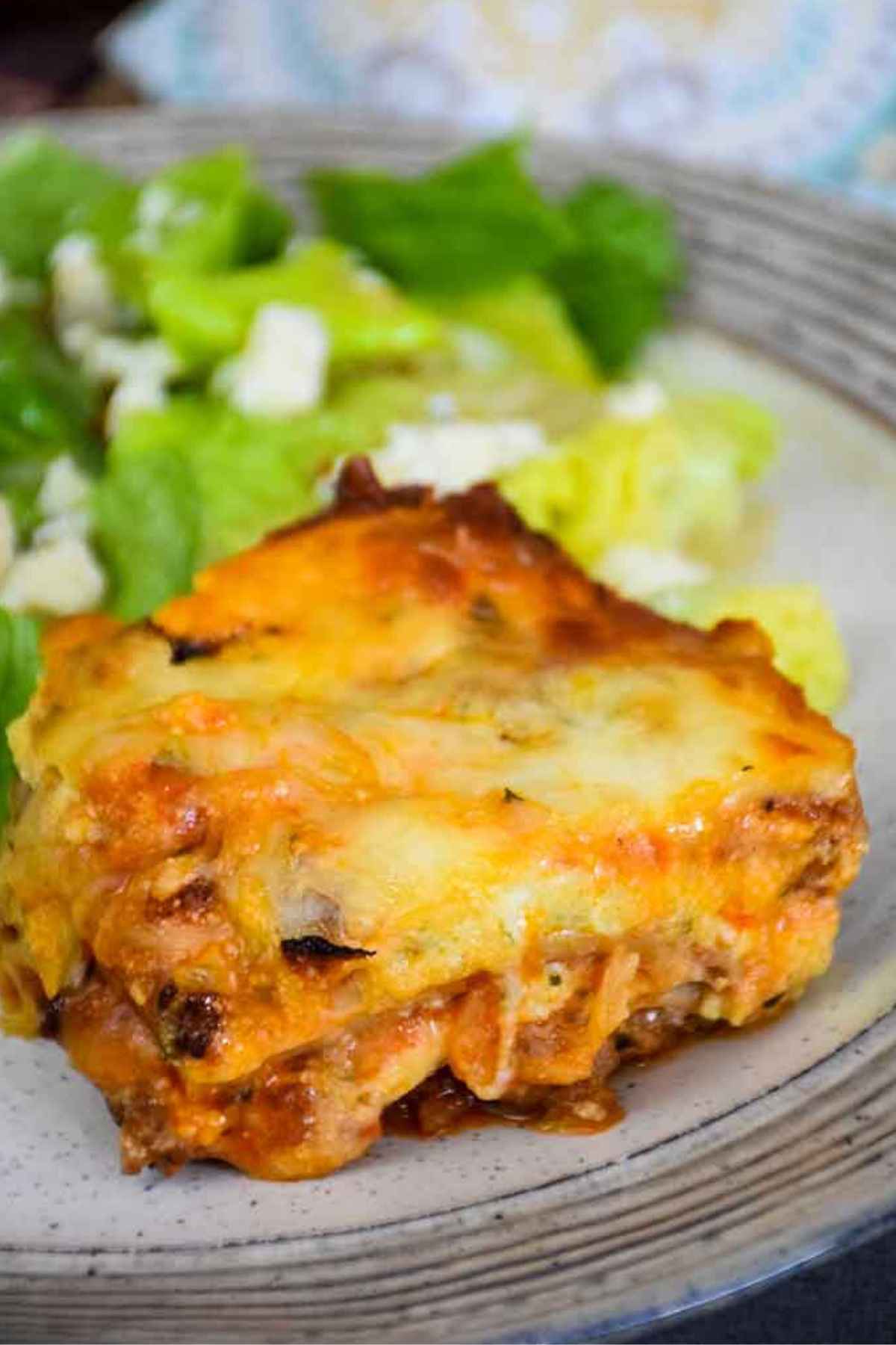 One serving Hearts of Palm Lasagna on a plate with a green salad in the background.