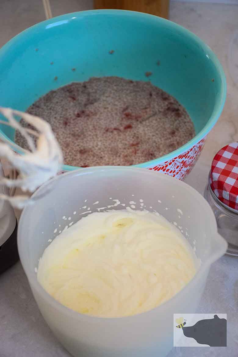 Bowl of heavy whipped cream with strawberry chia mixture in the background.