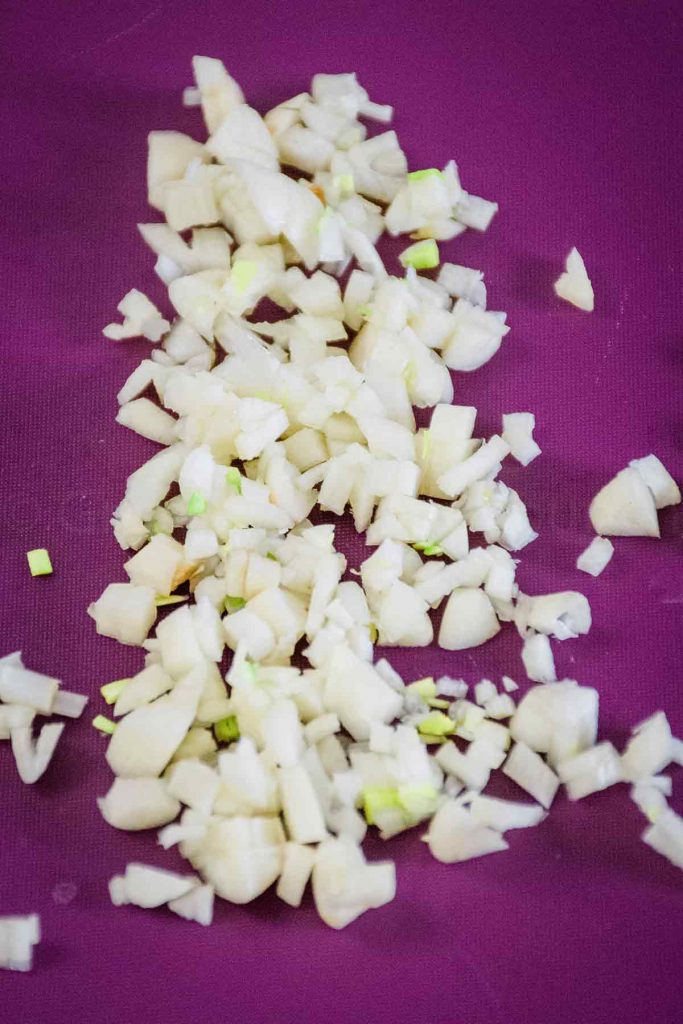 Chopped garlic on a purple mat.