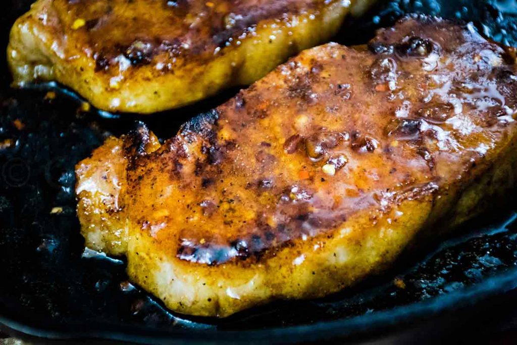 Cooked boneless pork in a skillet with a honey garlic glaze.