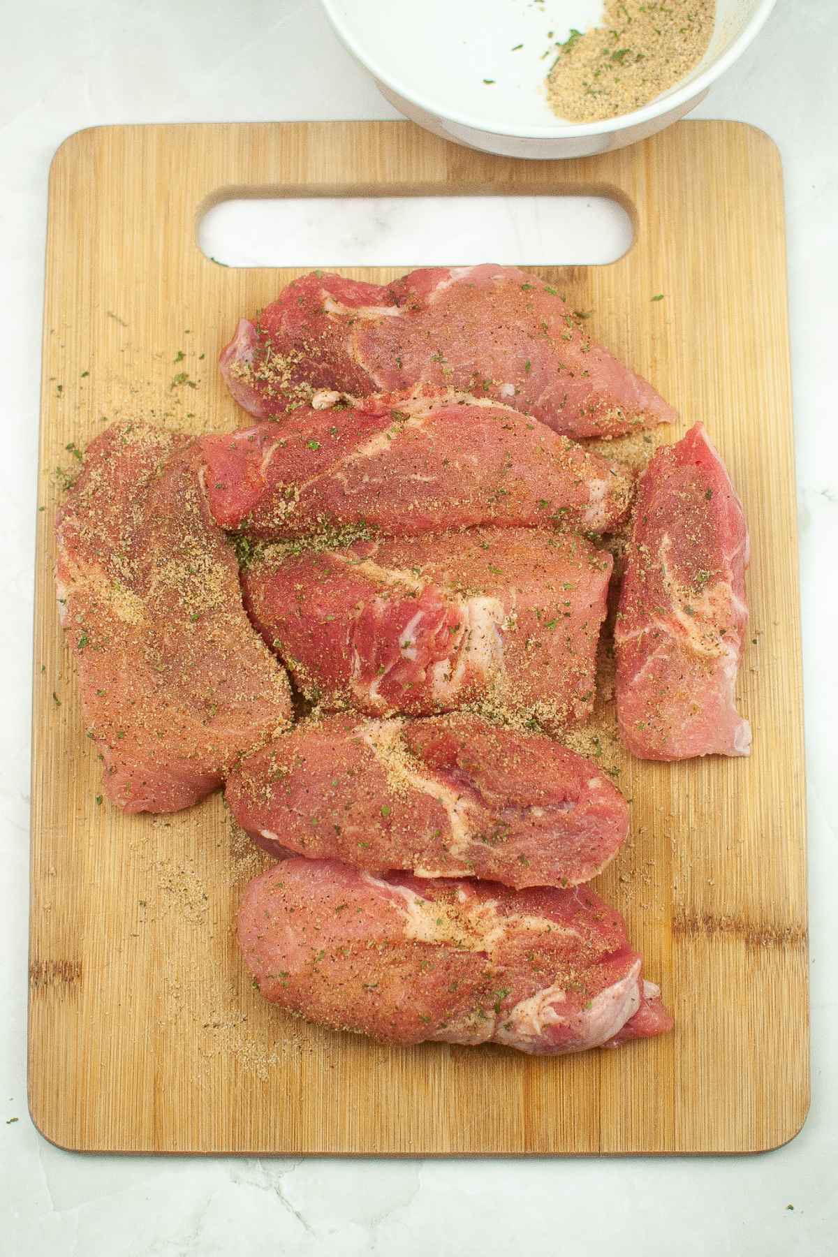 Seasoned meat on a cutting board.