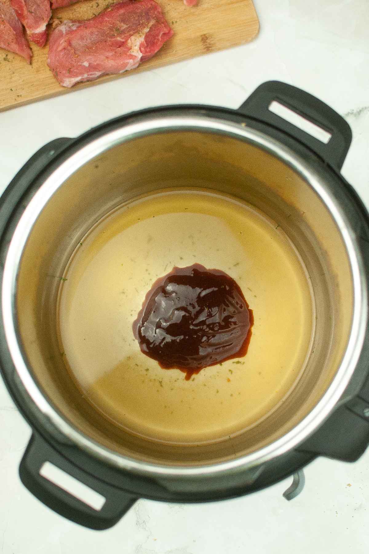 Instant Pot with chicken broth and barbecue sauce inside the pot.