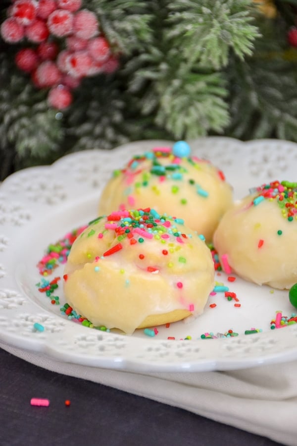 Italian Christmas Cookies decorated with pink and blue sprinkles on a white plate.