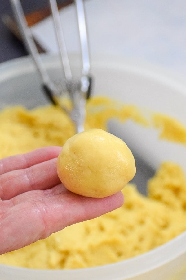 A hand holding a cookie dough ball.