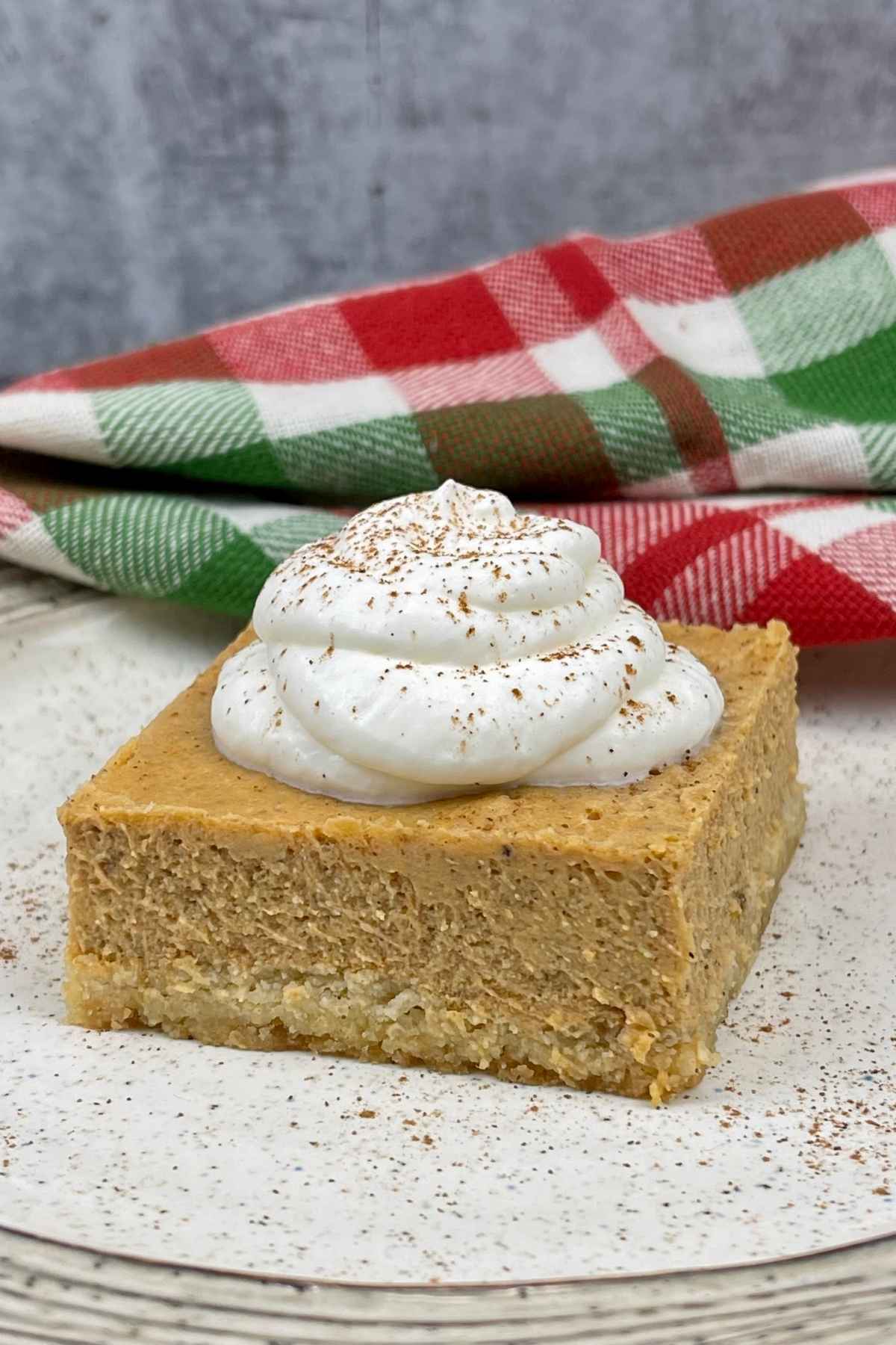 Keto Pumpkin Cheesecake Bar on a plate with a red, green and white napkin.