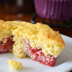 One Keto Raspberry Muffin cut in half on a white plate.