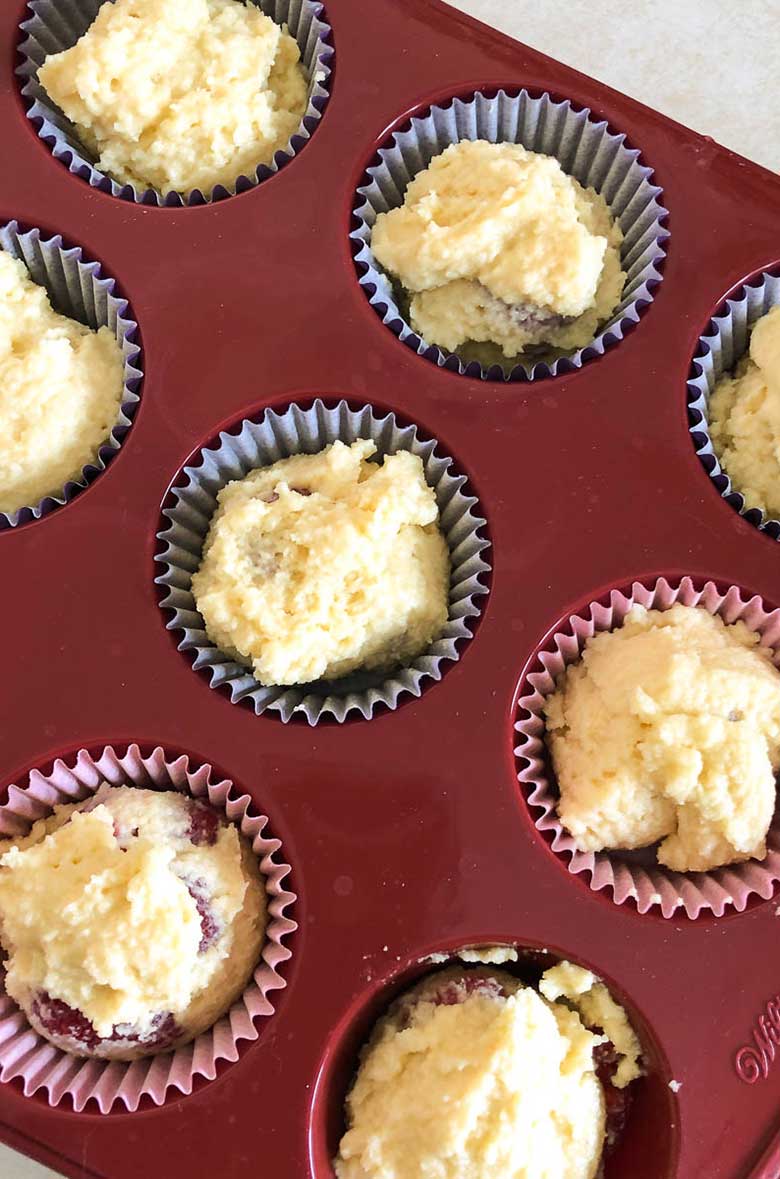 Muffin batter in paper liners in a muffin pan.