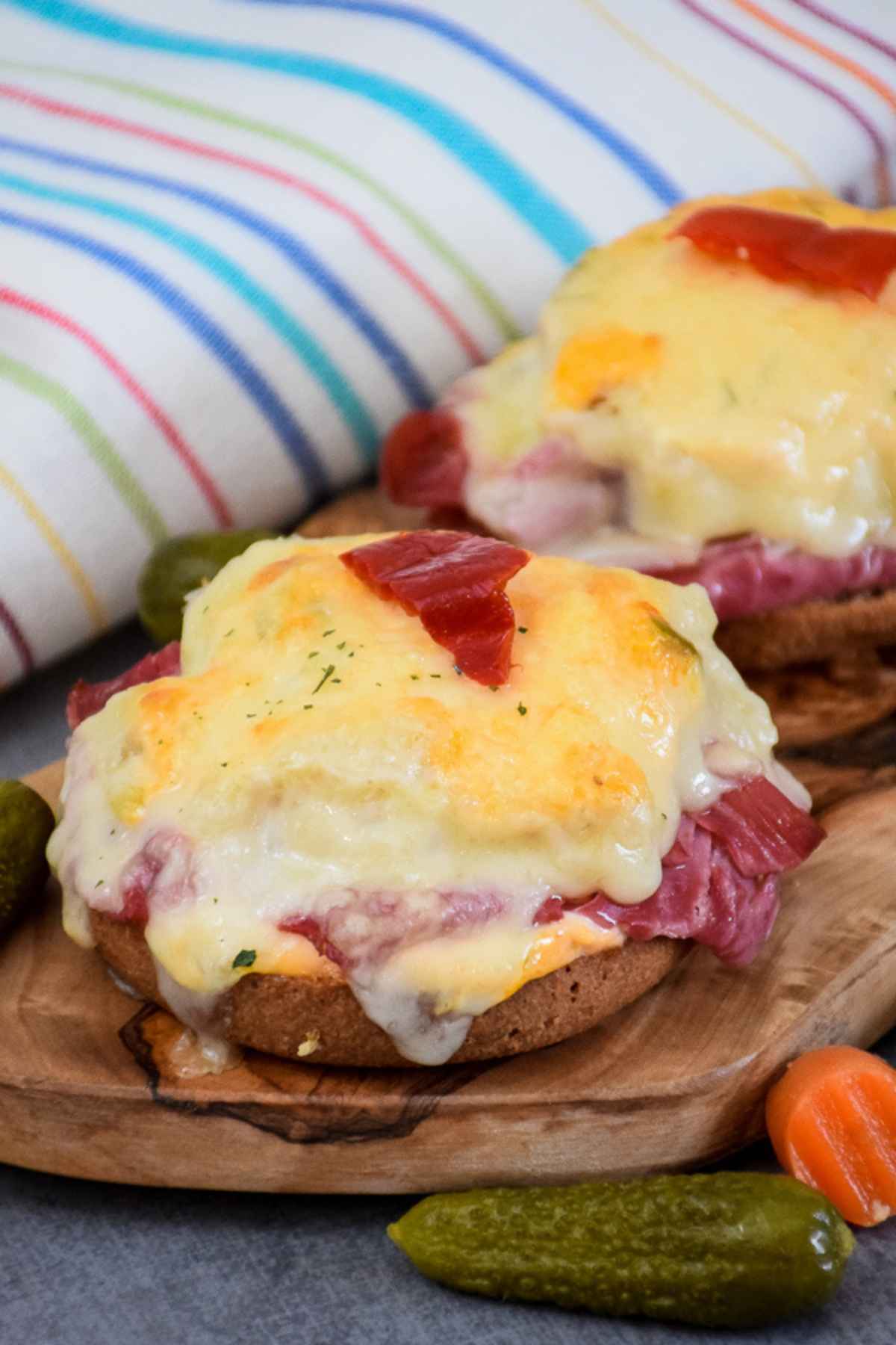 Two Open face keto reuben sandwiches on a brown tray with pickled veggie garnish.