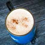 keto snickerdoodle coffee in a blue mug with cinnamon sprinkled on top of the coffee
