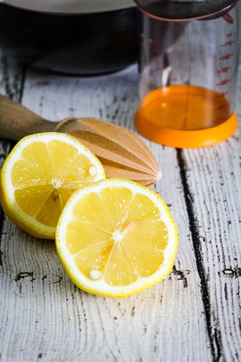 Lemon cut in half with citrus reamer behind it.