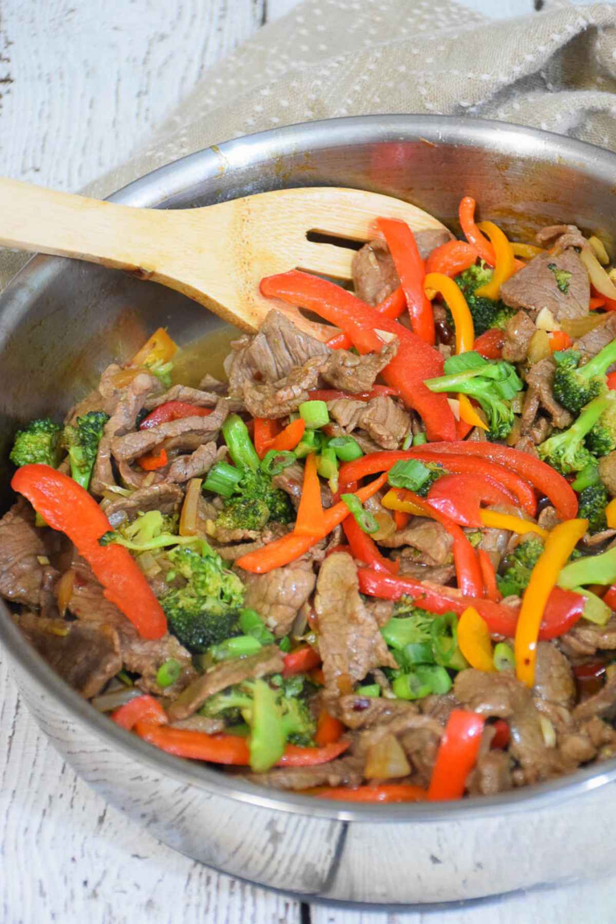 Low Carb Beef Stir Fry in a stainless steel skillet with a wooden spoon.