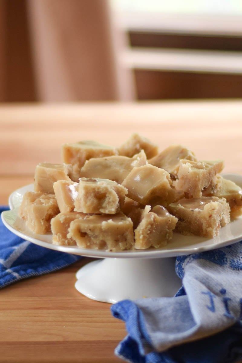 Maple walnut fudge on a footed white serving plate.