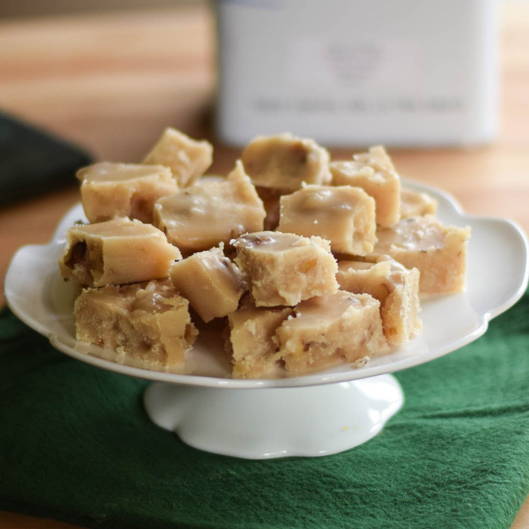 Maple walnut fudge on a footed white plate.